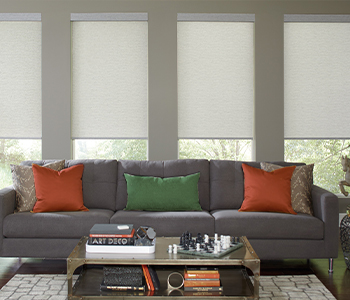 Off-white roller shades behind a long couch