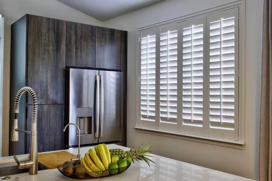 Homeowners use indoor window shutters in Boston when they want attractive and functional window treatments. Polywood shutters on a large kitchen window