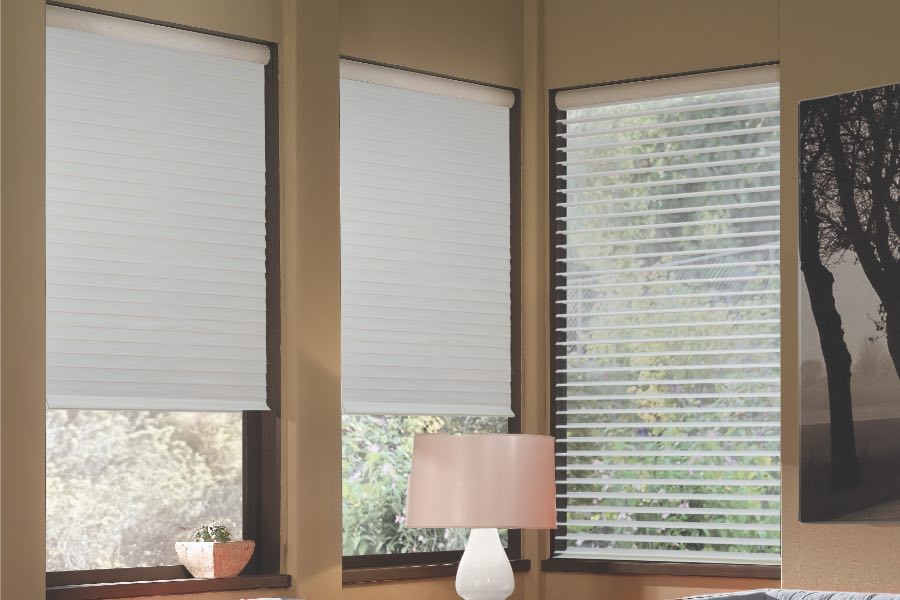 Opaque motorized window shades in Boston keep hot UV rays out of your home. Gray motorized sheer shades on corner windows next to gray furniture