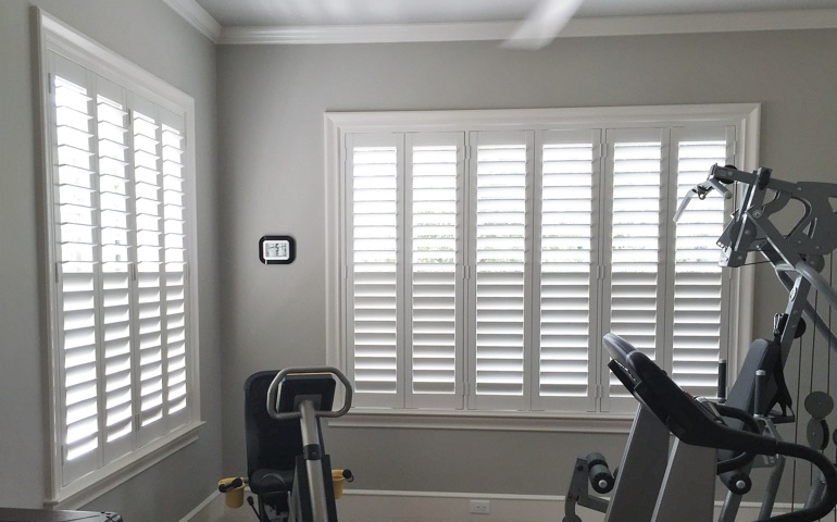 Draft-blocking window coverings are vital in rooms with windows on multiple walls. Boston exercise room with shuttered windows.