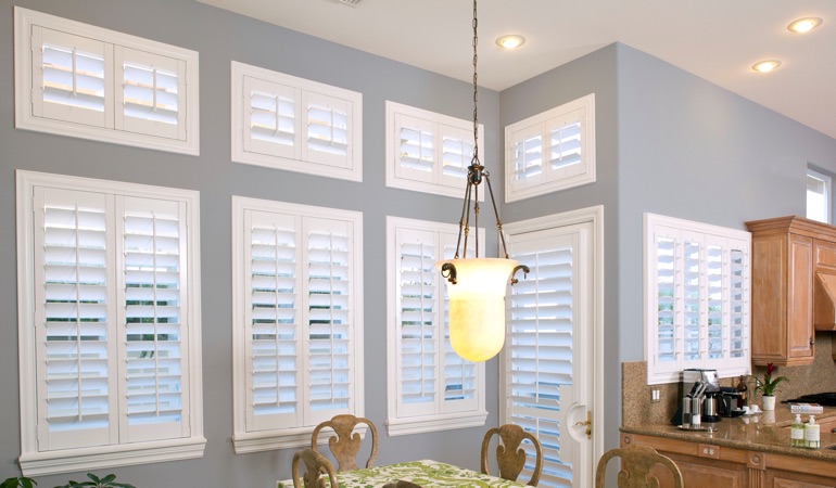Shutters can resolve both sun glare and heat loss problems. White plantation shutters in kitchen