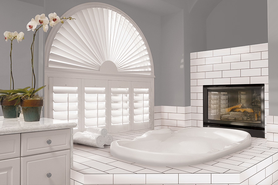 Explore our selection of window treatments for builders in Boston to find the perfect ones for your next construction project. White Polywood shutters on an arched bathroom window