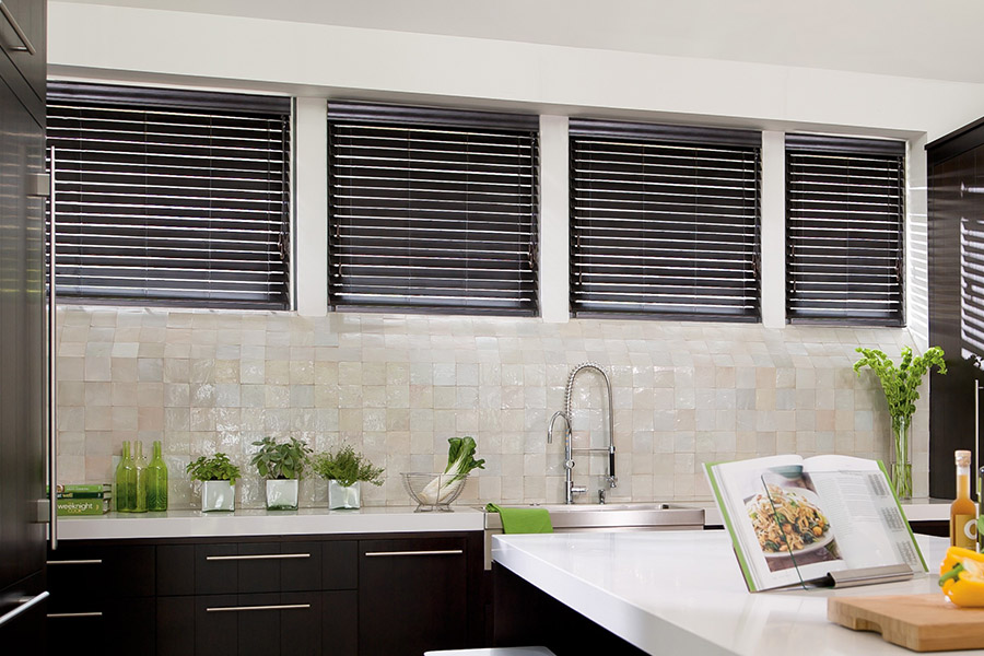 Choose custom Polywood faux wood blinds for your kitchen in Boston. Special shaped faux wood blinds in several windows above a sink.