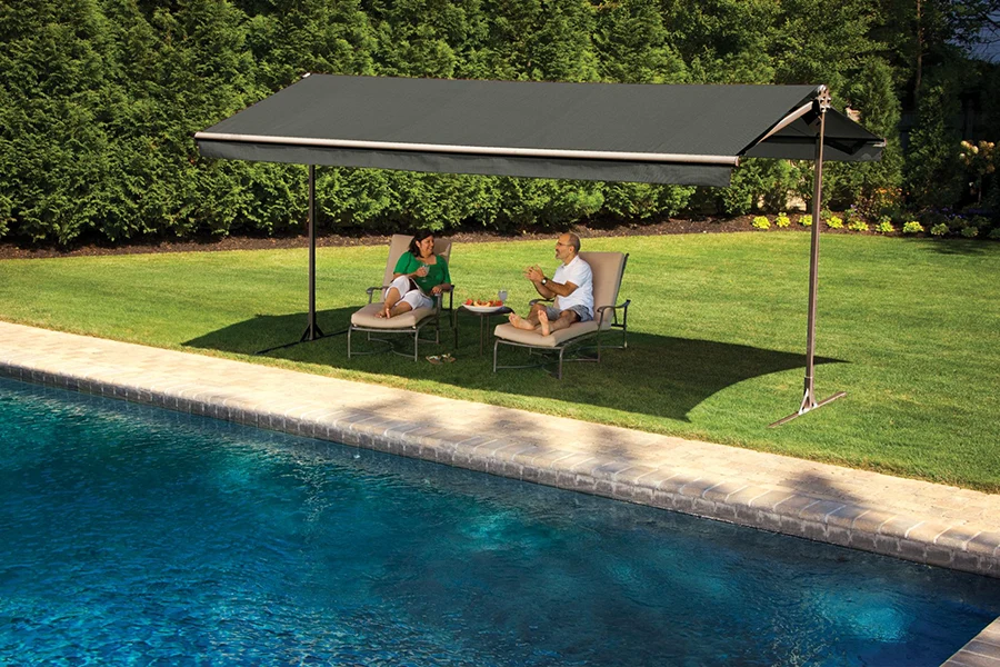 Two people lounging beside a pool under a freestanding awning