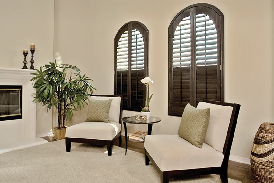 Dark wood shutters on two arched windows in a living room