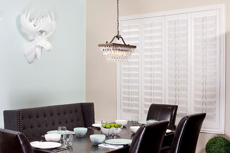 Polywood shutters block outside light and temperature transfer to keep you comfortable in your dining room. Closed white Polywood shutters on a dining room window